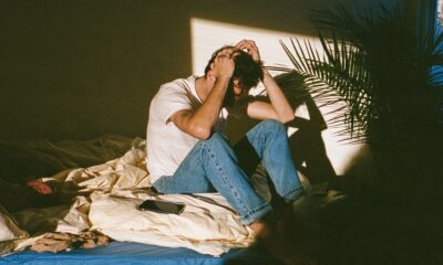 A man feeling like a failure while he sits on his bed