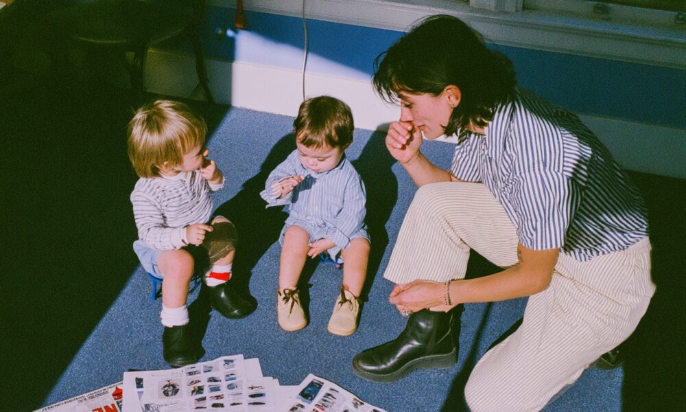 Child interacting with peers on a playground while a therapist observes and guides the session.