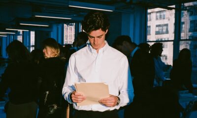 A CEO standing in his office holding a manila folder as he is facing legal challenges