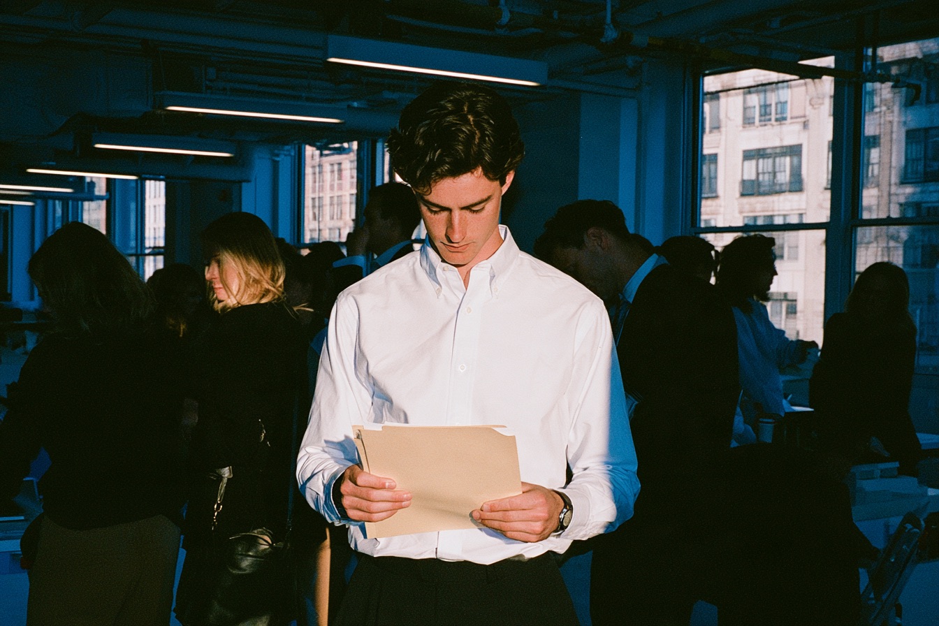 A CEO standing in his office holding a manila folder as he is facing legal challenges