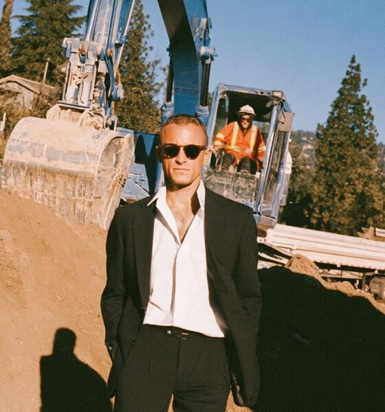 A male business owner standing in front of an excavator