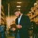 A man in his suit leading in a warehouse getting it organized