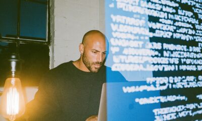 A man typing an article on his laptop with keywords projected in front of him