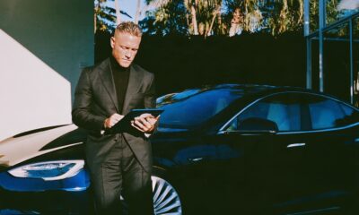 Man in a charcoal suit standing next to a sleek car