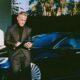 Man in a charcoal suit standing next to a sleek car