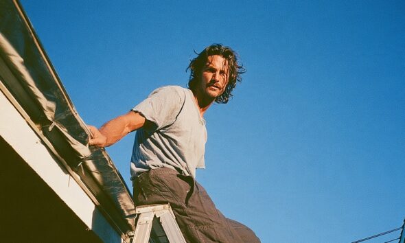 Man on a ladder fixing the gutter of his luxury house roof