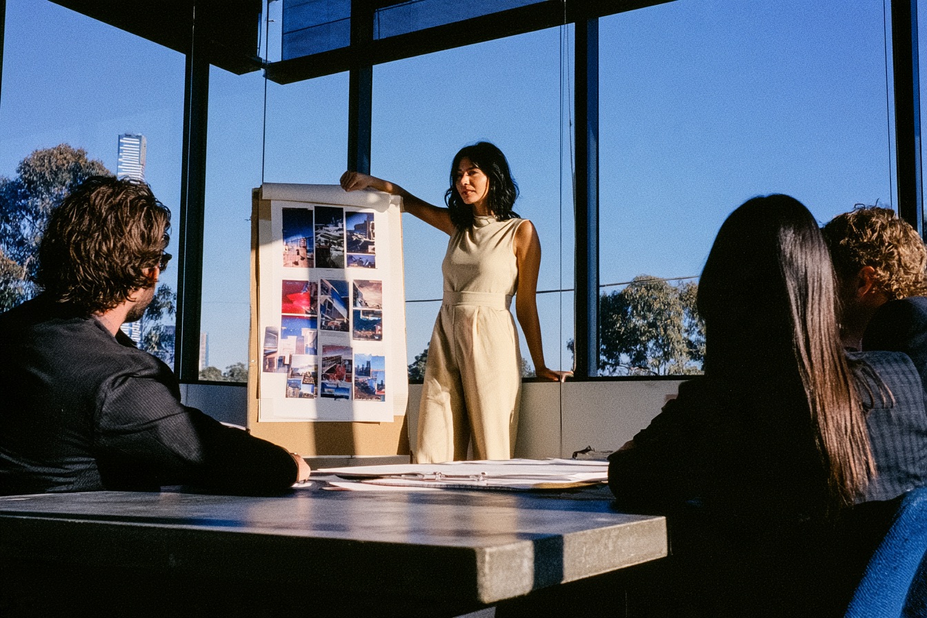 Woman standing at the front of a room pitching her marketing strategy to her creative team