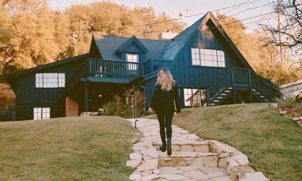 Woman standing out the front of a house in the fall
