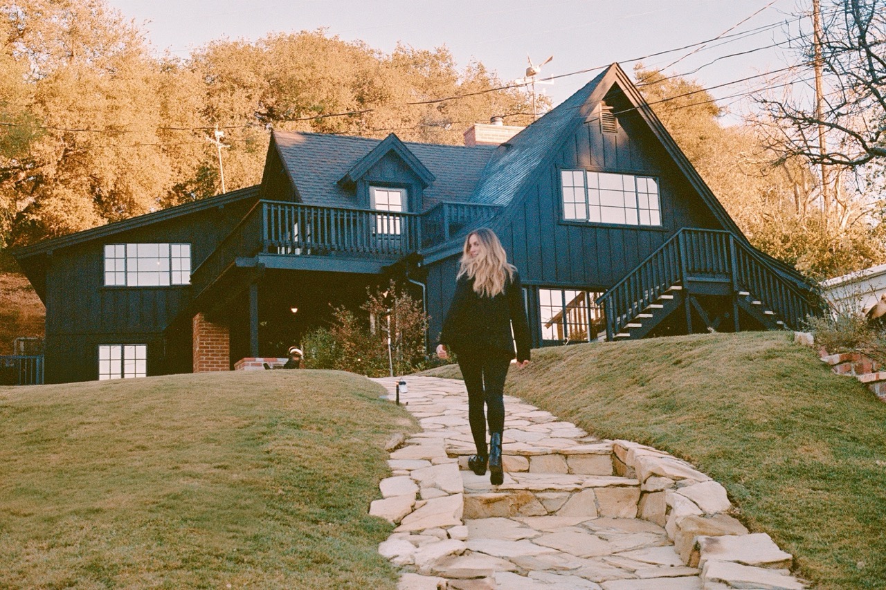 Woman standing out the front of a house in the fall