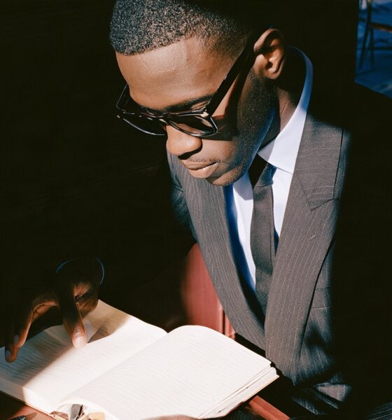 a black male founder in his mid-30s working early in the morning at a minimalist dark walnut desk to improve his life and ahcive more success