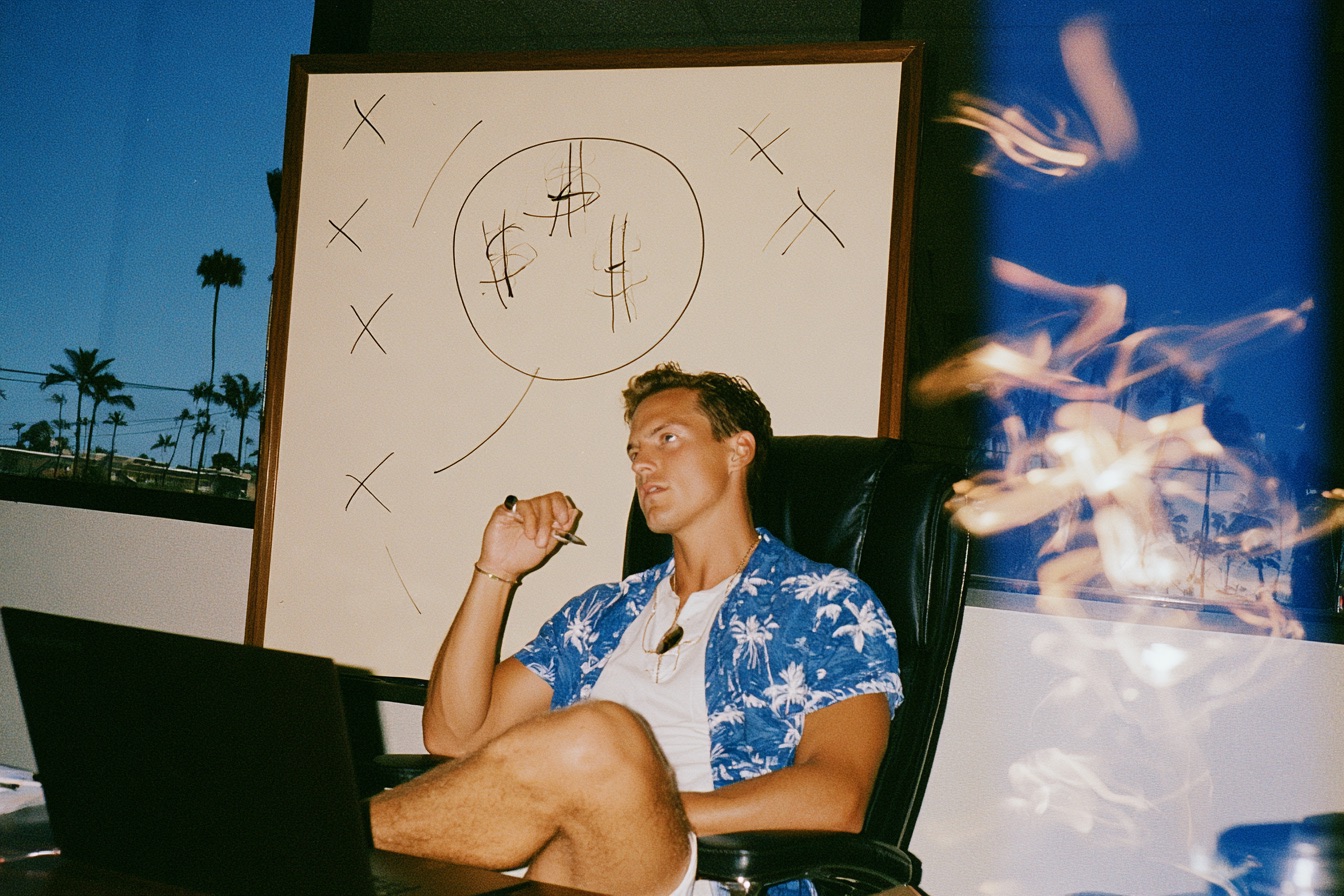 a focused male entrepreneur selling in his sleek office with a laptop open on the desk