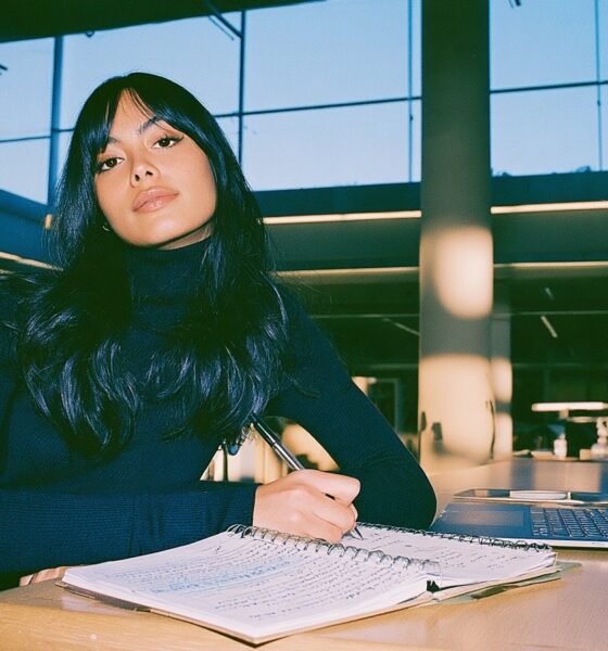 a focused young researcher sitting at a clean, sunlit wooden desk in an academic library