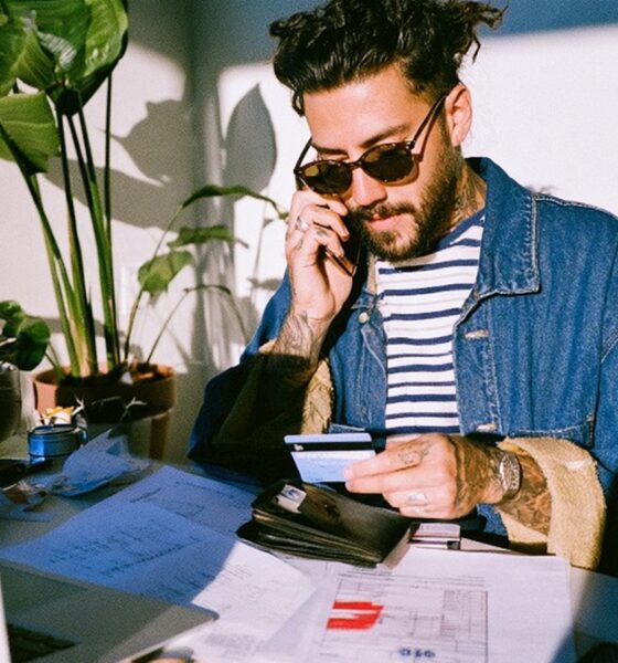 a male entrepreneur with his wallet out in his neat modern home office space applying for a loan