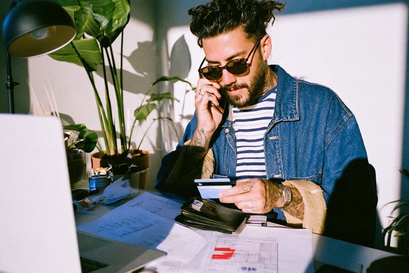 a male entrepreneur with his wallet out in his neat modern home office space applying for a loan