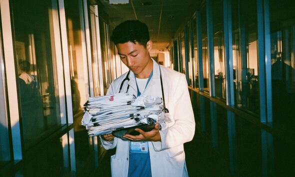 a medical tech founder standing in a sleek glass walled hospital administrative wing