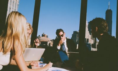 three executives from sales, marketing and finance sitting in a sleek glass walled boardroom.